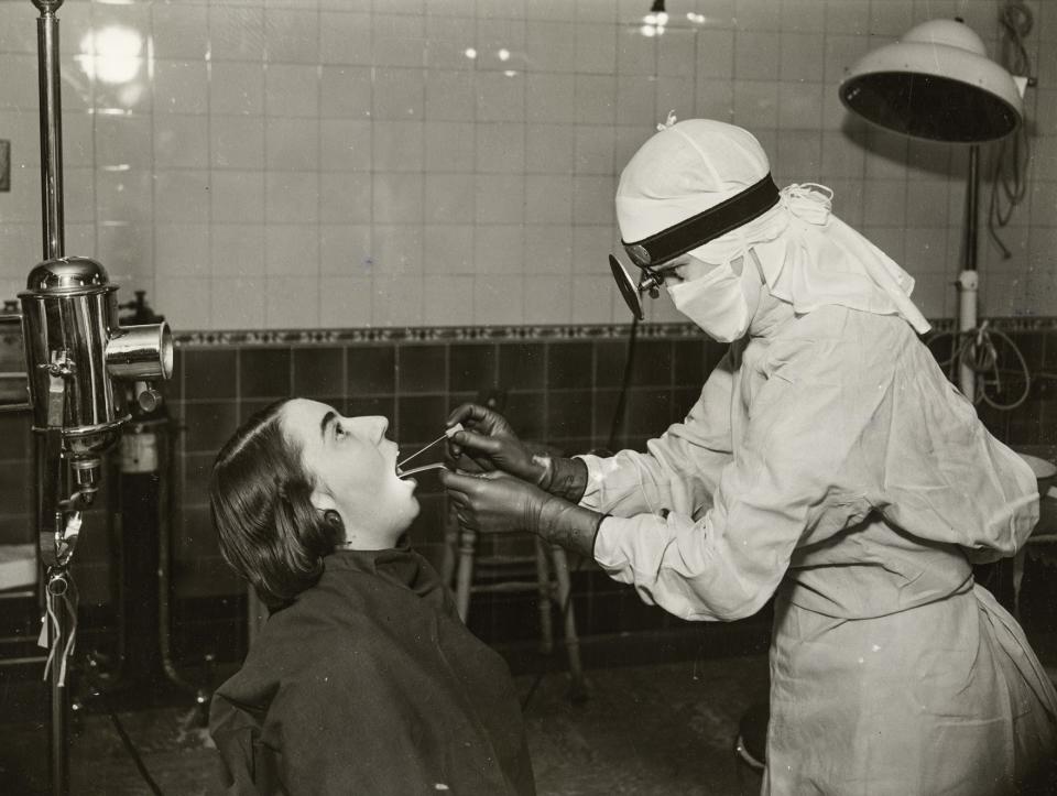 A nurse in a white gown and cap taking a throat swab from a patient, at Middlesex Hospital, Mortimer Street, Greater London Authority, W1