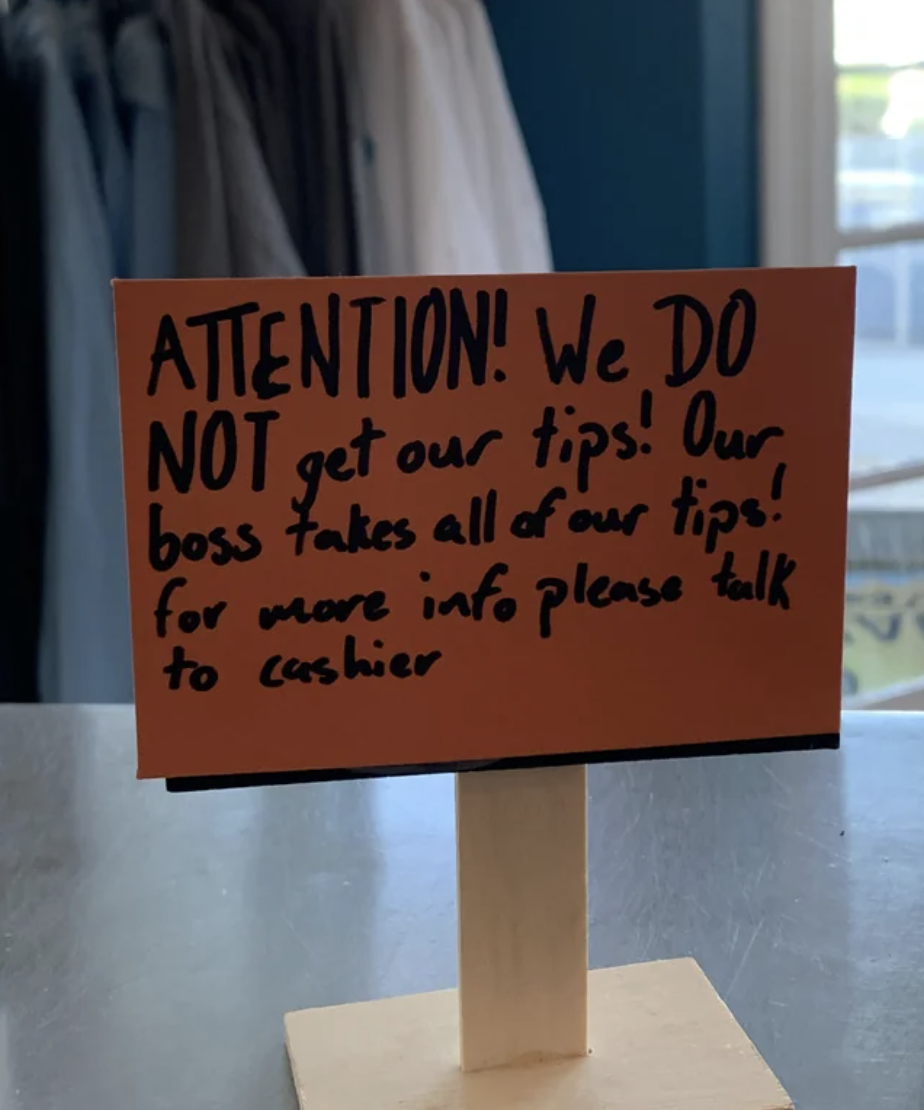 A sign letting customers know the cashiers' boss takes all their tips