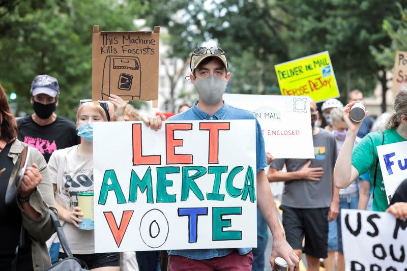 FILE PHOTO: Demonstrators march to the condo of Postmaster General Louis DeJoy, to protest against changes in the postal service, in Washington