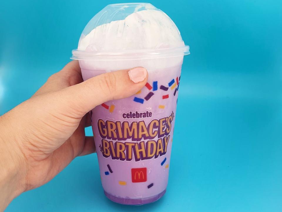 the Grimace milkshake from McDonald's, which the the color purple, against a blue background