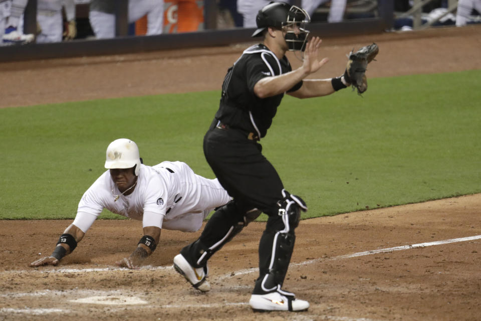 Miami Marlins' Starlin Castro, left, scores past Philadelphia Phillies catcher J.T. Realmuto on a double hit by Neil Walker during the fifth inning of a baseball game, Friday, Aug. 23, 2019, in Miami. (AP Photo/Lynne Sladky)