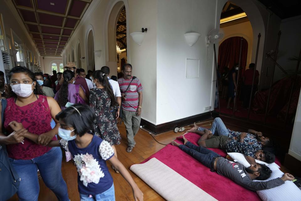 People look around as protestors sleep on the floor at President Gotabaya Rajapaksa's official residence on the second day after it was stormed in Colombo, Sri Lanka, Monday, July 11, 2022. Sri Lanka is in a political vacuum for a second day Monday with opposition leaders yet to agree on who should replace its roundly rejected leaders, whose residences are occupied by protesters, angry over the country's economic woes.(AP Photo/Eranga Jayawardena)