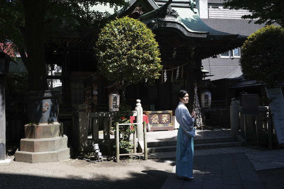 In this May 8, 2020, photo, Ryoki Ono, head priest, stands at the precincts after performing a livestream prayer during a 10-day trial of "online shrine" visit program at Onoterusaki Shrine in downtown Tokyo, allowing its visitors to join rituals from their homes. The shrine also accepted from worshipers their prayer messages, which were printed on a virtual wooden tablet each and offered to the Shinto gods to keep away evil spirits and the epidemic. (AP Photo/Eugene Hoshiko)