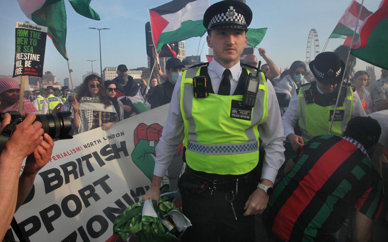 A police officer leaves the crowd who are blocking Waterloo Bridge after confiscating a bag of smoke flares