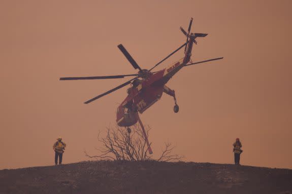 An S-64E Sikorsky Skycrane firefighting helicopter flies past firefighters on a smoky ridge near Burbank on September 3, 2017.