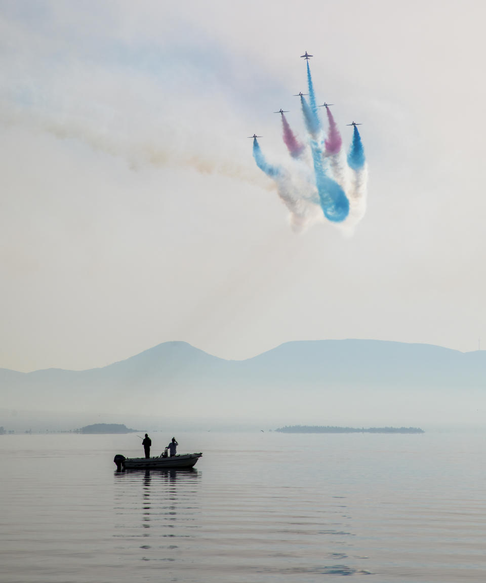 Image of the Royal Air Force Aerobatic Team, the Red Arrows, seen here performing the 'Goose' manoeuvre on a very still morning whilst fisherman watch on in Chalkoutsi, Greece (Picture: UK MOD/Crown 2019)