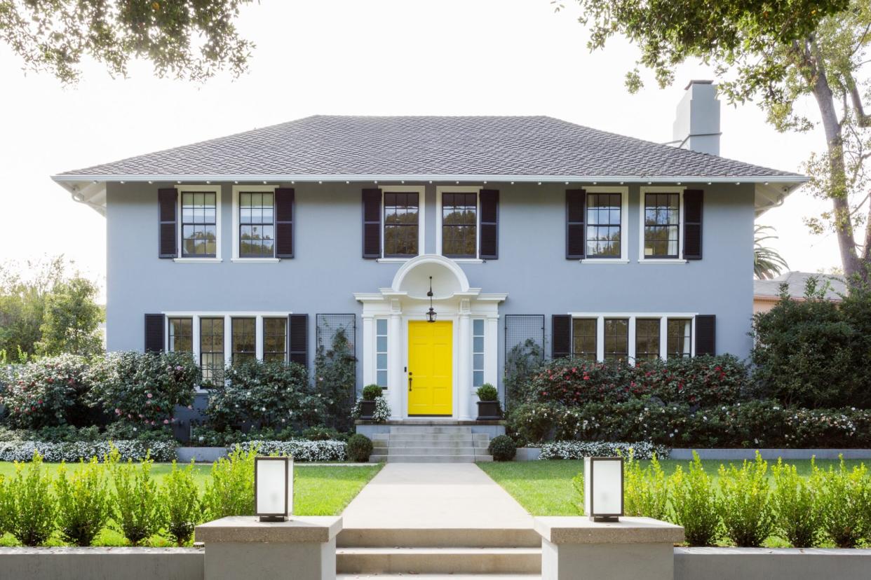 blue house with yellow door and pretty landscaping