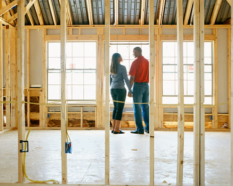 a couple stands in a home under construction