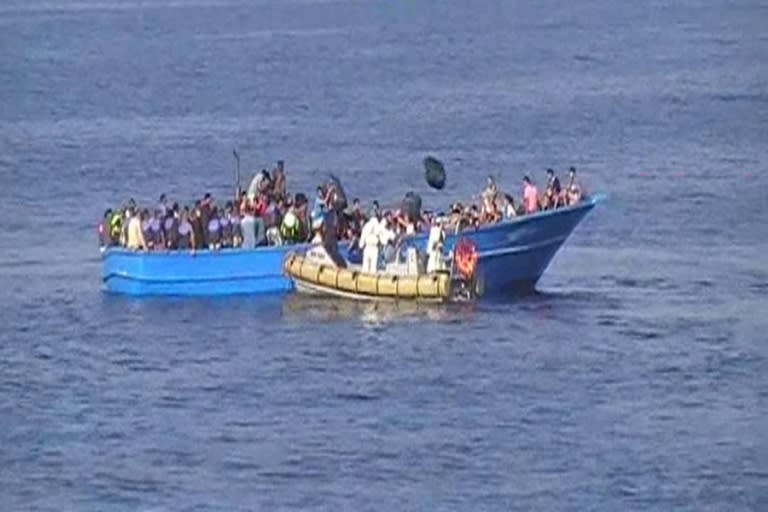 An Italian Navy inflatable boat (front) rescues migrants on a fishing boat off Libya on August 15, 2015