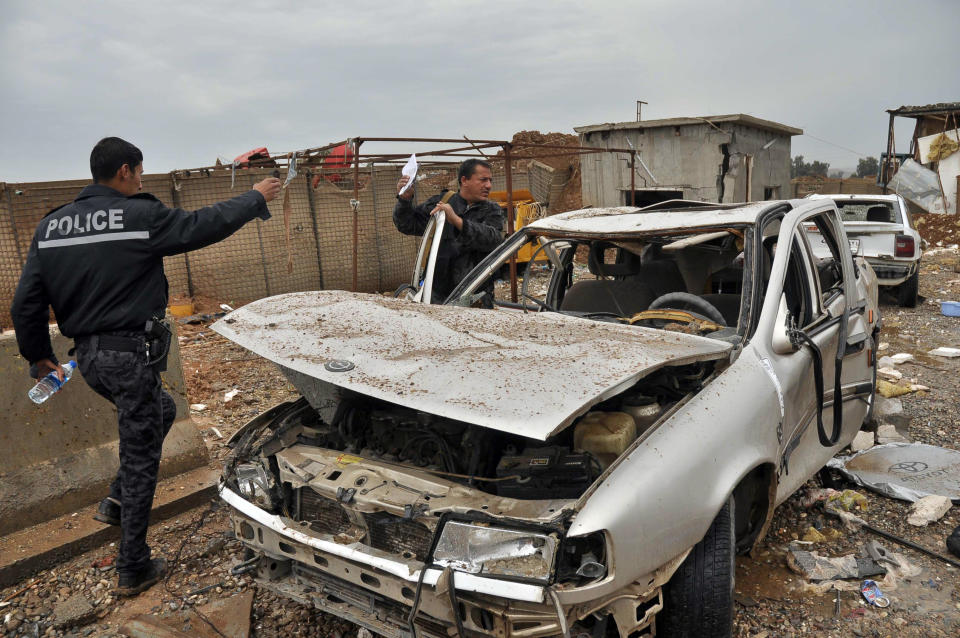 Iraqi security forces inspect the site of a suicide car bombing in the northern town of Dibis, near the city of Kirkuk, 290 kilometers (180 miles) north of Baghdad, Iraq, Sunday, April 13, 2014. A suicide bomber rammed his explosives-laden car into a security checkpoint, killing and wounding policemen and civilians, authorities said. (AP Photo/Emad Matti)