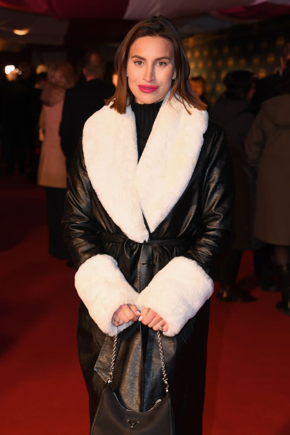 ferne mccann in january 2023 in a black coat with large white fluffy sleeves and collar