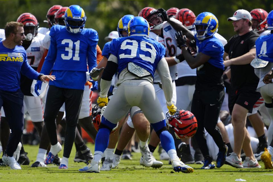 Los Angeles Rams defensive tackle Aaron Donald (99) regains his footing with two Bengals helmets in his hands after a third scuffle escalates into a brawl during a joint preseason camp practice between the Cincinnati Bengals and the Los Angeles Rams at Paycor Stadium in Cincinnati on Thursday, Aug. 25, 2022. Practice was ended early after a third scuffle turned into a broader fight between players on both teams.