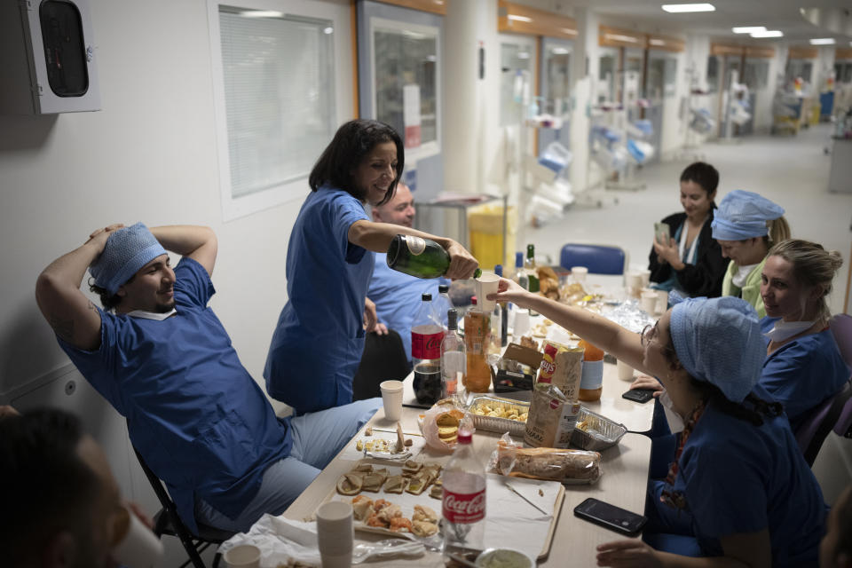 Nurse Bess Tribout, center, pours champagne to celebrate the new year in the COVID-19 intensive care unit at the la Timone hospital in Marseille, southern France, Saturday, Jan. 1, 2022. (AP Photo/Daniel Cole)