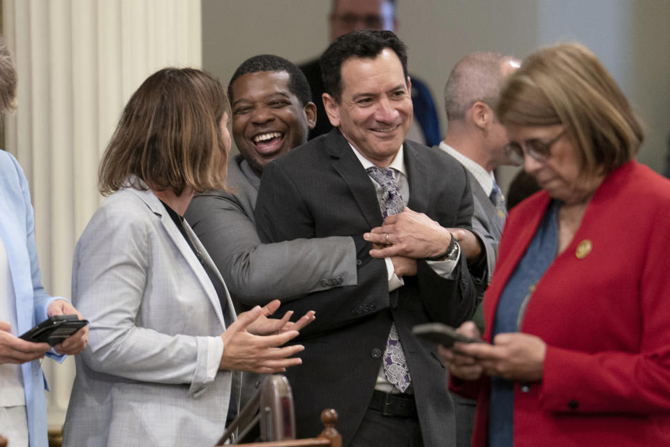 FILE – Assemblymember Corey Jackson, second from left, gives Assembly speaker Anthony Rendon, third from left, a hug during the Assembly session at the state Capitol in Sacramento, California, on June 1, 2023. Rendon will step down as speaker on Friday, June 30, 2023, giving way to Assemblymember Robert Rivas. Rendon has been in office since 2016, making him the second-longest serving speaker in state history. (AP Photo/Rich Pedroncelli, File)