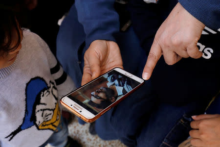 A family member holds a mobile phone displaying a photo of Naeem Rashid who was killed along with his son Talha Naeem in the Christchurch mosque attack in New Zealand, during a condolence gathering at the family's home in Abbottabad, Pakistan March 17, 2019. REUTERS/Akhtar Soomro