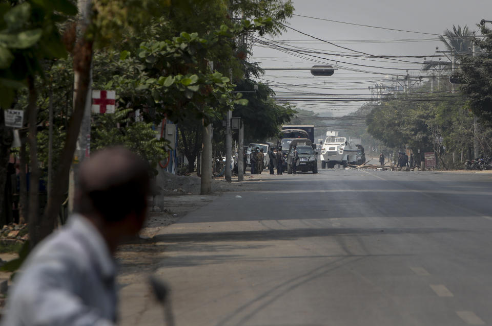 A man watches as a convoy of soldiers and policemen arrive at a demonstration in Mandalay, Myanmar, Wednesday, March 10, 2021. (AP Photo)