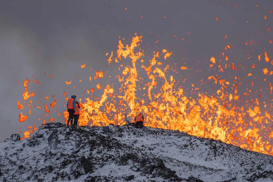 <p>AP Photo/Marco Di Marco</p> Scientist of the University of Iceland take measurements and samples standing on the ridge in front of the active part of the eruptive fissure of an active volcano in Grindavik on Iceland