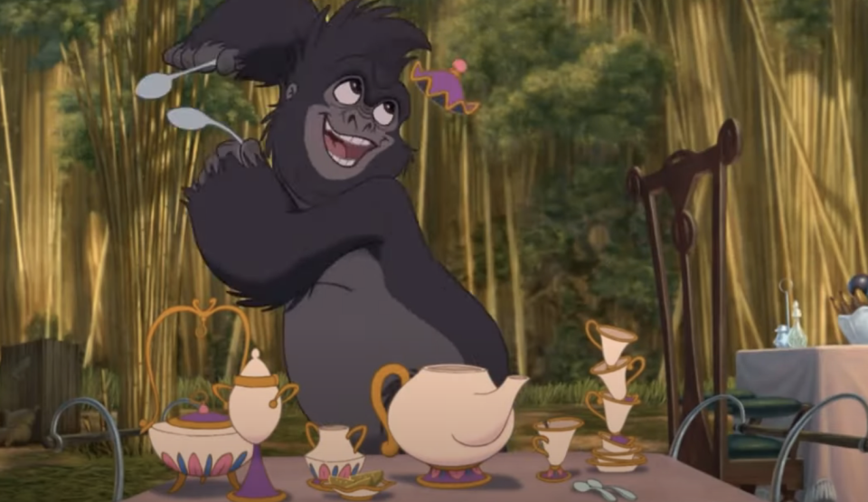 one of the apes dancing in front of a table set for tea