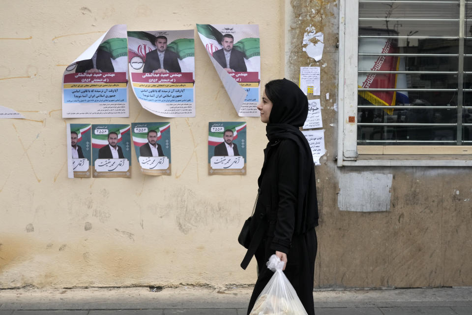 A woman walks past electoral posters of candidates for the March 1, parliamentary election, in downtown Tehran, Iran, Thursday, Feb. 22, 2024. Candidates for Iran's parliament began campaigning Thursday in the country's first election since the bloody crackdown on the 2022 nationwide protests that followed the death of 22-year-old Mahsa Amini in police custody. (AP Photo/Vahid Salemi)