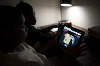 Isaiah Schneider, 9, left, and his brother Adam, 7, complete a level on their learning game played on a tablet computer, in their bedroom, Wednesday, Dec. 8, 2021, in the Brooklyn borough of New York. Their mother April Schneider says she is lucky her two oldest children attend the same school and can share technology. "When one computer is down, we can us the other," said Schneider. "There needs to be more computers. More staff. More outreach." (AP Photo/John Minchillo)