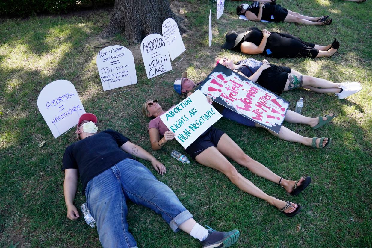 demonstrators lie on the ground in front of tombstone signs supporting abortion rights