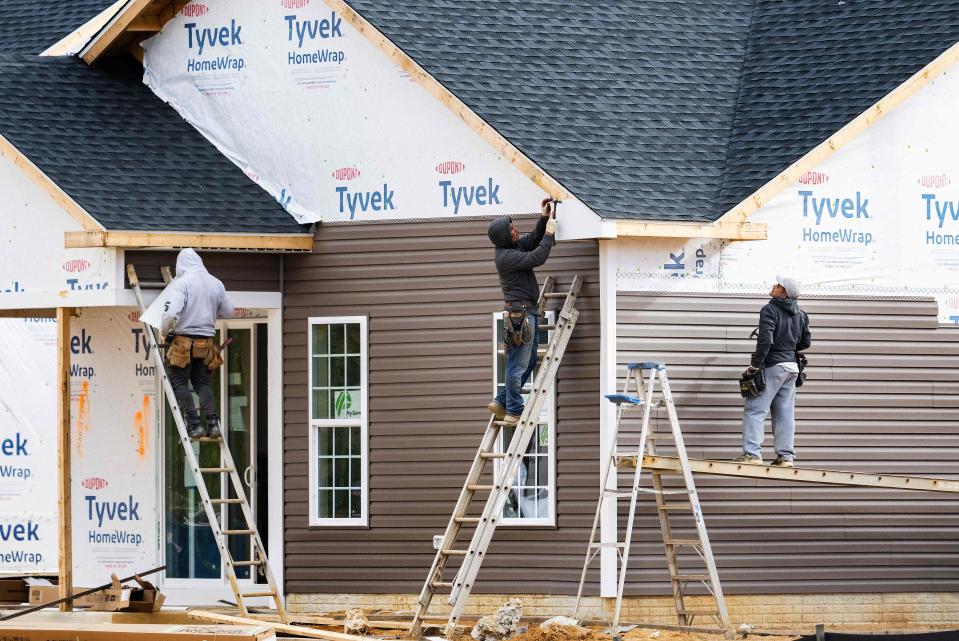 Workers attach siding to a house at a new home construction site in Trappe, Maryland. (Credit: Jim Watson, / AFP via Getty Images).