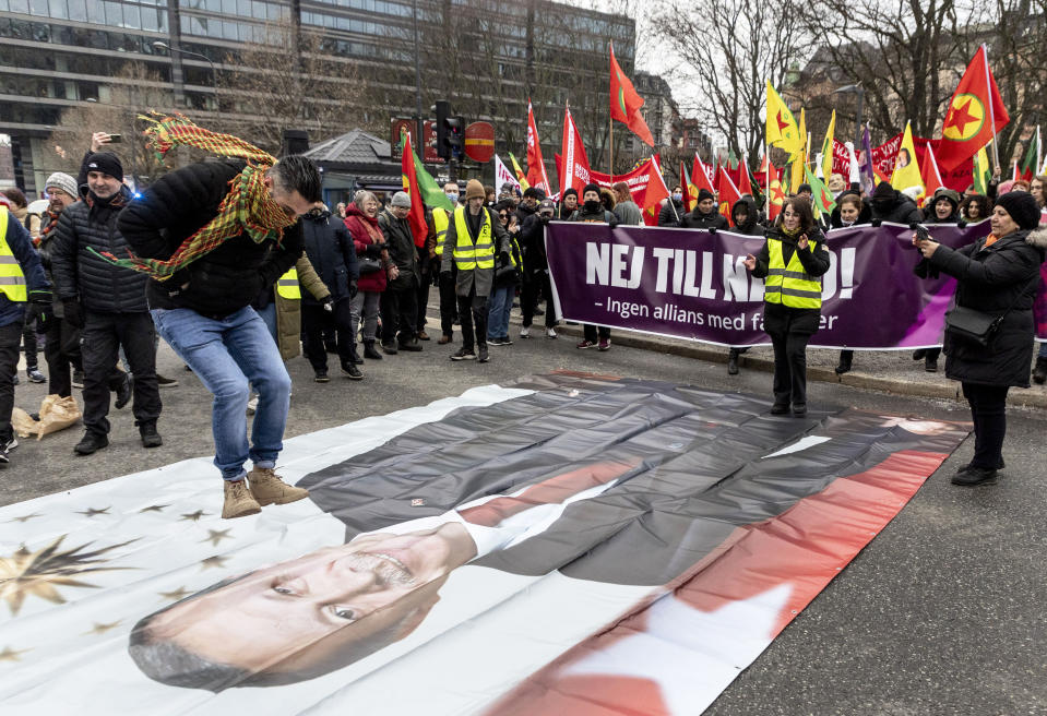 A protestor prepares to jump on a banner with the image of Turkish President Recep Tayyip Erdogan during a demonstration organised by The Kurdish Democratic Society Center in Sweden, as Sweden seeks Turkey's approval to join NATO, in Stockholm, Saturday, Jan. 21, 2023. Demonstrations took place in Sweden that could complicate its efforts to persuade Turkey to approve its NATO accession. A far-right activist from Denmark has received permission from police to stage a protest on Saturday outside the Turkish Embassy, where he intends to burn the Quran, Islam’s holy book. (Christine Olsson/TT News Agency via AP)