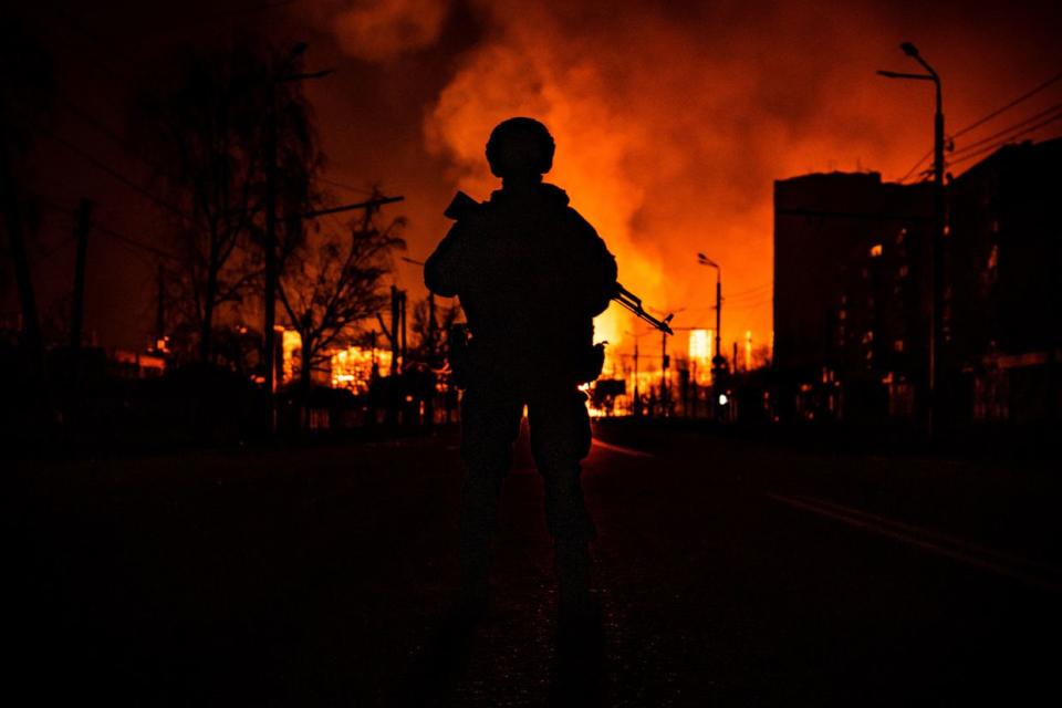 A member of the Ukrainian special forces is seen in silhouette as he stands while a gas station burns after Russian attacks in the city of Kharkiv on March 30, 2022. (Fadel Senna /AFP via Getty Images)