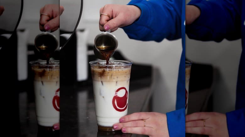 Barista pouring iced cup of coffee