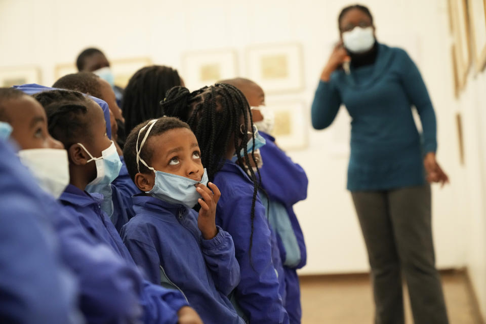 Schoolchildren look at paintings done in the 1940s and 1950s by young Black students at Cyrene Mission School at the National Gallery of Zimbabwe, Wednesday Aug. 3, 2022. The paintings are part of a historic exhibit, "The Stars are Bright," now showing in Zimbabwe for the first time since the collection left the country more than 70 years ago. (AP Photo/Tsvangirayi Mukwazhi)