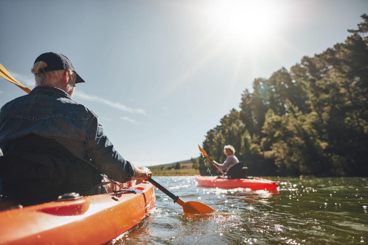 Image of senior couple canoeing in the lake on a sunny day. Kayakers in the lake paddling.