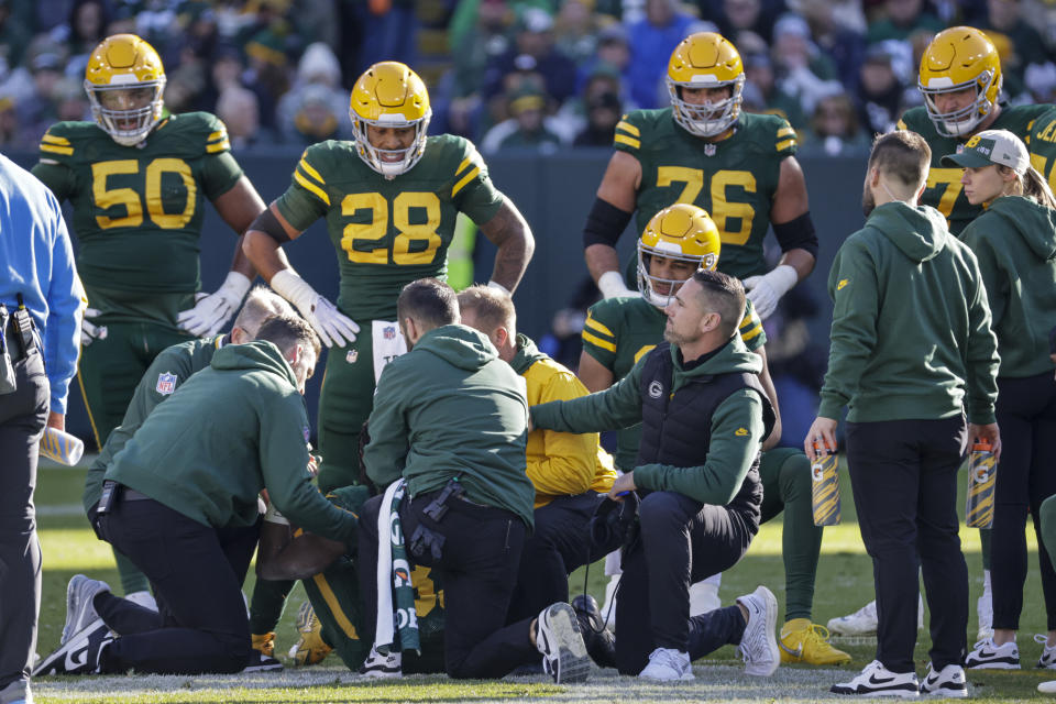 Green Bay Packers head coach Matt LaFleur, bottom right, and quarterback Jordan Love, behind LaFleur, kneel down as trainers tend to running back Aaron Jones during the first half of an NFL football game against the Los Angeles Chargers, Sunday, Nov. 19, 2023, in Green Bay, Wis. (AP Photo/Mike Roemer)