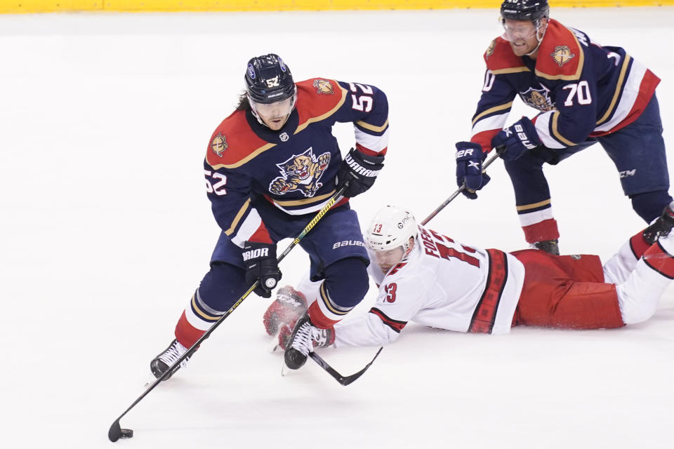 Florida Panthers defenseman MacKenzie Weegar (52) takes control of the puck from Carolina Hurricanes left wing Warren Foegele (13) during the second period at an NHL hockey game, Saturday, Feb. 27, 2021, in Sunrise, Fla. (AP Photo/Marta Lavandier)