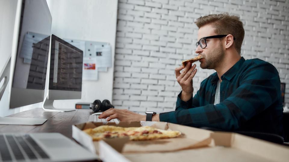 Hombre comiendo frente al computador 