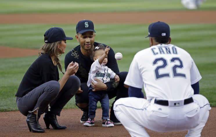 Entertainer John Legend, center, and his wife Chrissy Teigen help their daughter Luna Stephens throw out the ceremonial first pitch to Seattle Mariners' Robinson Cano before a baseball game against the Minnesota Twins Tuesday, June 6, 2017, in Seattle. (AP Photo/Elaine Thompson)