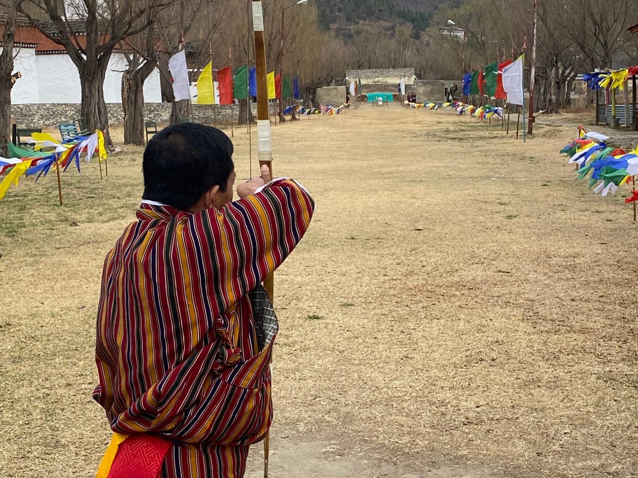 A man shooting an arrow while competing in archery in Bhutan.