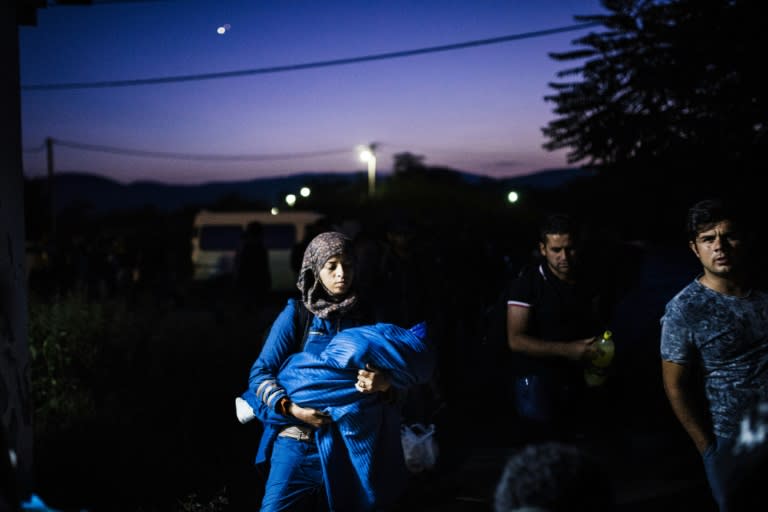 A migrant woman holds her baby as she leaves a train at a railway station on the Tabanovce border crossing between Macedonia and Serbia, on July 1, 2015