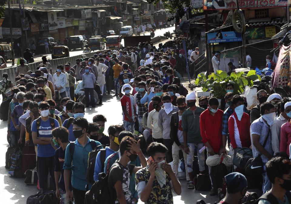 FILE - In this Friday, May 22, 2020 file photo migrant workers line up to board buses for their onward journey by train to their home states, at Dharavi, one of Asia's largest slums, in Mumbai, India. (AP Photo/Rafiq Maqbool)