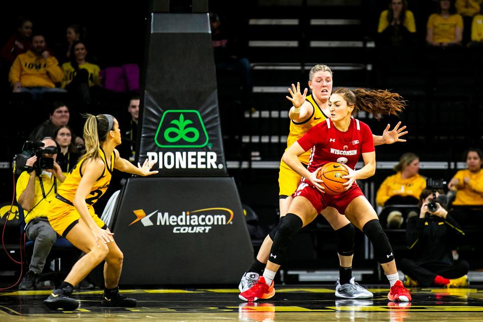 Iowa center Monika Czinano, second from right, and guard Gabbie Marshall, left, defend Wisconsin guard Brooke Schramek during a NCAA Big Ten Conference women’s basketball game, Wednesday, Feb. 15, 2023, at Carver-Hawkeye Arena in Iowa City, Iowa.