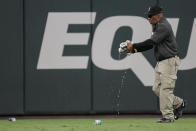 A security person picks up cans thrown on the field by fans after a umpire call during the eighth inning of Game 1 of a baseball NL Division Series between the Atlanta Braves and the Philadelphia Phillies, Saturday, Oct. 7, 2023, in Atlanta. (AP Photo/John Bazemore)