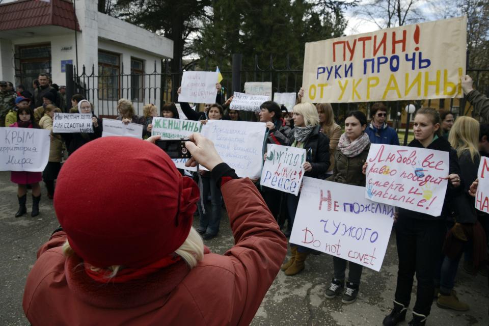 A woman takes a photograph of an anti-war picket in the Crimean city of Simferopol