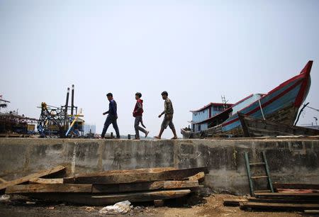 Men walk along the sea wall in Muara Baru, north Jakarta, September 30, 2014. REUTERS/Darren Whiteside