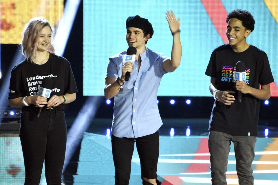 FILE - In this April 25, 2019, file photo, Cameron Boyce, center, speaks at WE Day California, as Macy Lillard, left, and Jazzy Satten look on at The Forum in Inglewood, Calif. Actor Cameron Boyce, known for his roles in the Disney Channel franchise “Descendants” and the Adam Sandler “Grown Ups” movies, died Saturday, July 6, 2019, at his home in Los Angeles, according to his spokesperson. He was 20. (Photo by Chris Pizzello/Invision/AP, File)