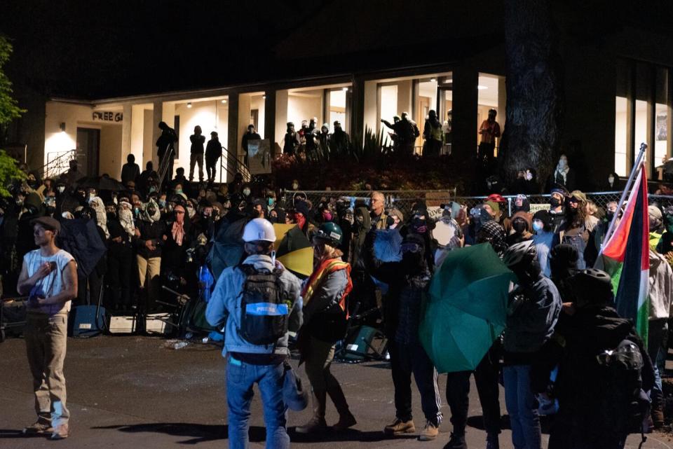 A crowd of students protesters in front of a campus building.