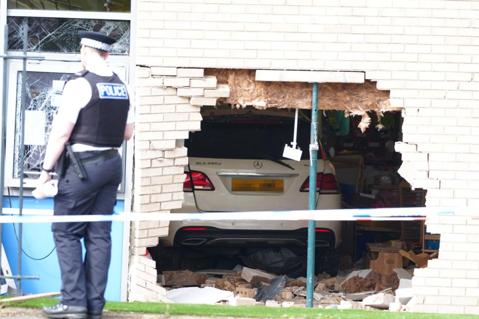 Police officers stand next to the damage after the Mercedes appeared to have crashed through the wall into a classroom (Peter Byrne/PA Wire)