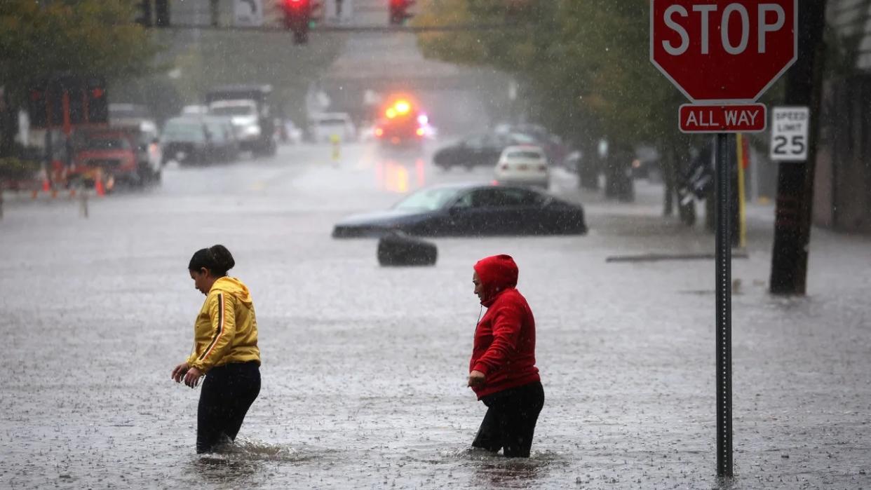 Los residentes caminan a través de las aguas de la inundación en el suburbio neoyorquino de Mamaroneck, en el condado de Westchester, Nueva York, este viernes.