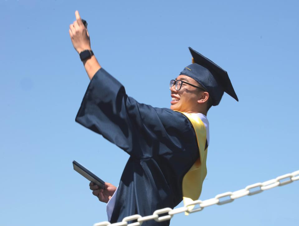 Graduating senior Justin Chuong pauses onstage to take a selfie after receiving his diploma during graduation ceremonies Saturday, June 4, 2022, at Plymouth North High School.