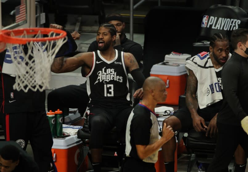 The Clippers' Paul George (13), seated next to Kawhi Leonard, cheers toward the end of the win over Utah on June 12, 2021.