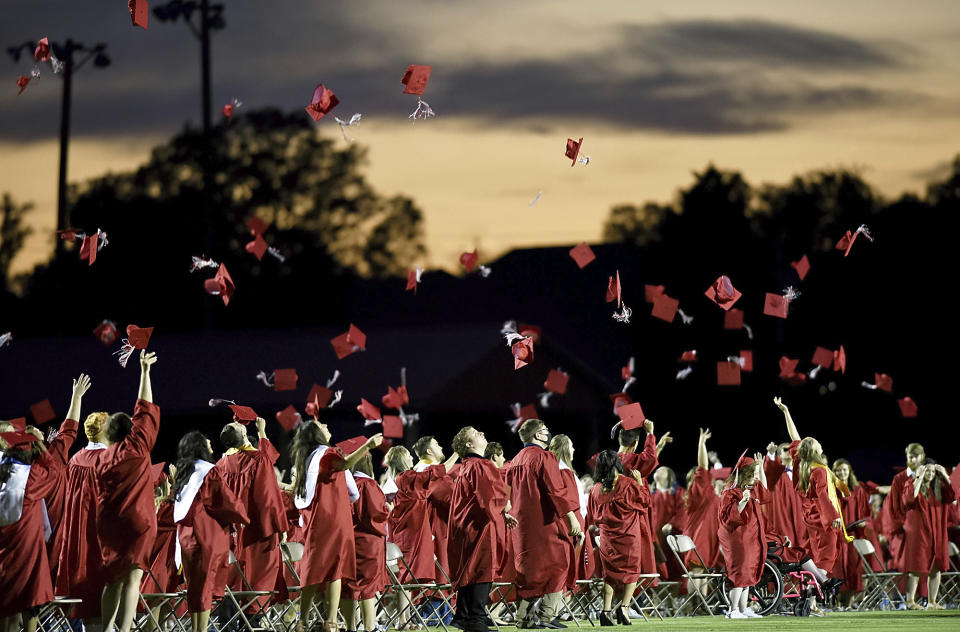 FILE - Red mortarboards fly into the evening sky at Heritage High School's commencement ceremony Friday, July 24, 2020, in Maryville Tenn. High school graduation rates dipped in at least 20 states after the first full school year disrupted by the pandemic, according to a new analysis by Chalkbeat. (Scott Keller/The Daily Times via AP, File, File)