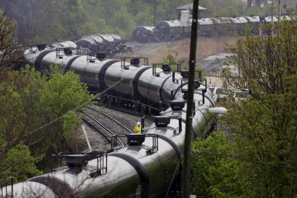 Firefighters and rescue workers work along the tracks where several CSX tanker cars carrying crude oil derailed and caught fire along the James river near downtown in Lynchburg, Va., Wednesday, April 30, 2014. Nearby buildings were evacuated for a time, but officials said there were no injuries and the city on its website and Twitter said firefighters on the scene made the decision to let the fire burn out. (AP Photo/Steve Helber)